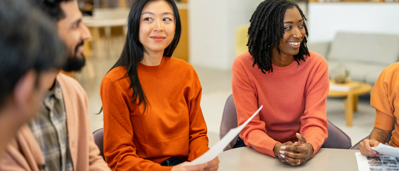 5 colleagues sit together, discussing notes on paper